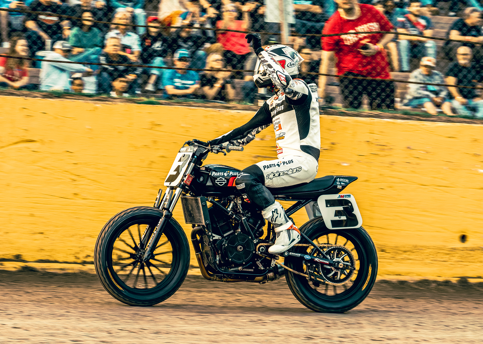 Briar Bauman waves at the crowd in the stands while riding his motorcycle after a race