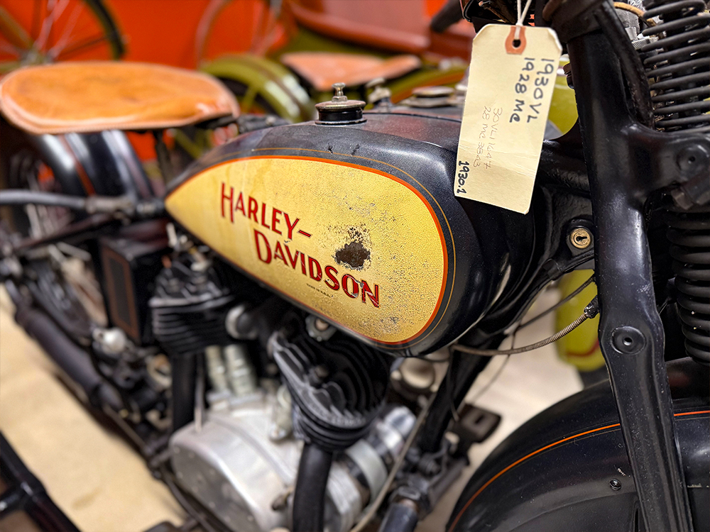 Close-up of vintage Harley-Davidson motorcycle fuel tank with worn paint and hanging tag