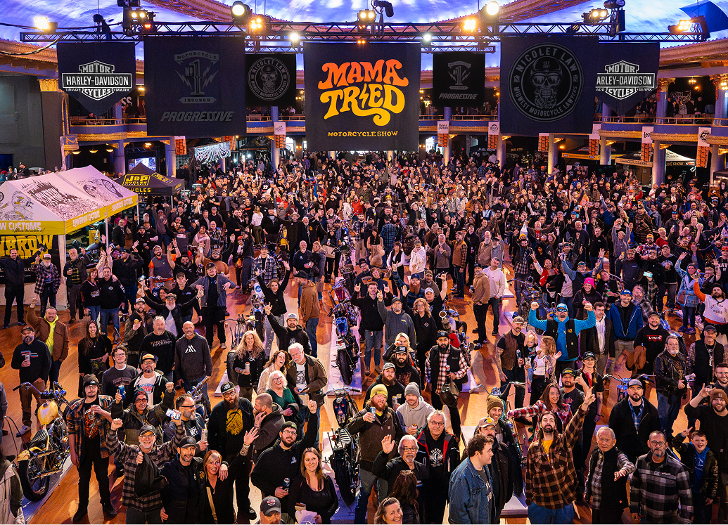 A wide shot of a large crowd waving and cheering to the camera at Mama Tried