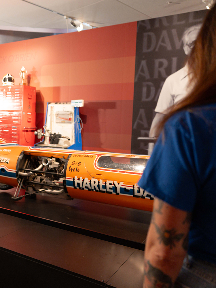 Visitor viewing Harley-Davidson motorcycle engine exhibit in museum gallery