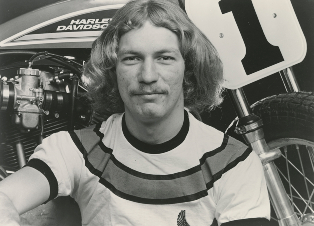 Close-up portrait of Jay Springsteen seated beside a motorcycle displaying number 1