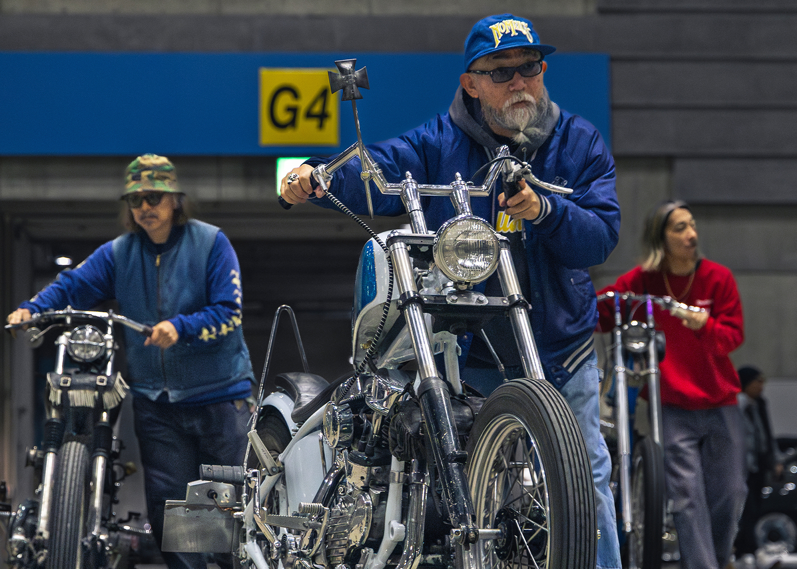 Three builders push their custom motorcycles into the show space at the Mooneyes Yokohama Rod Custom Show