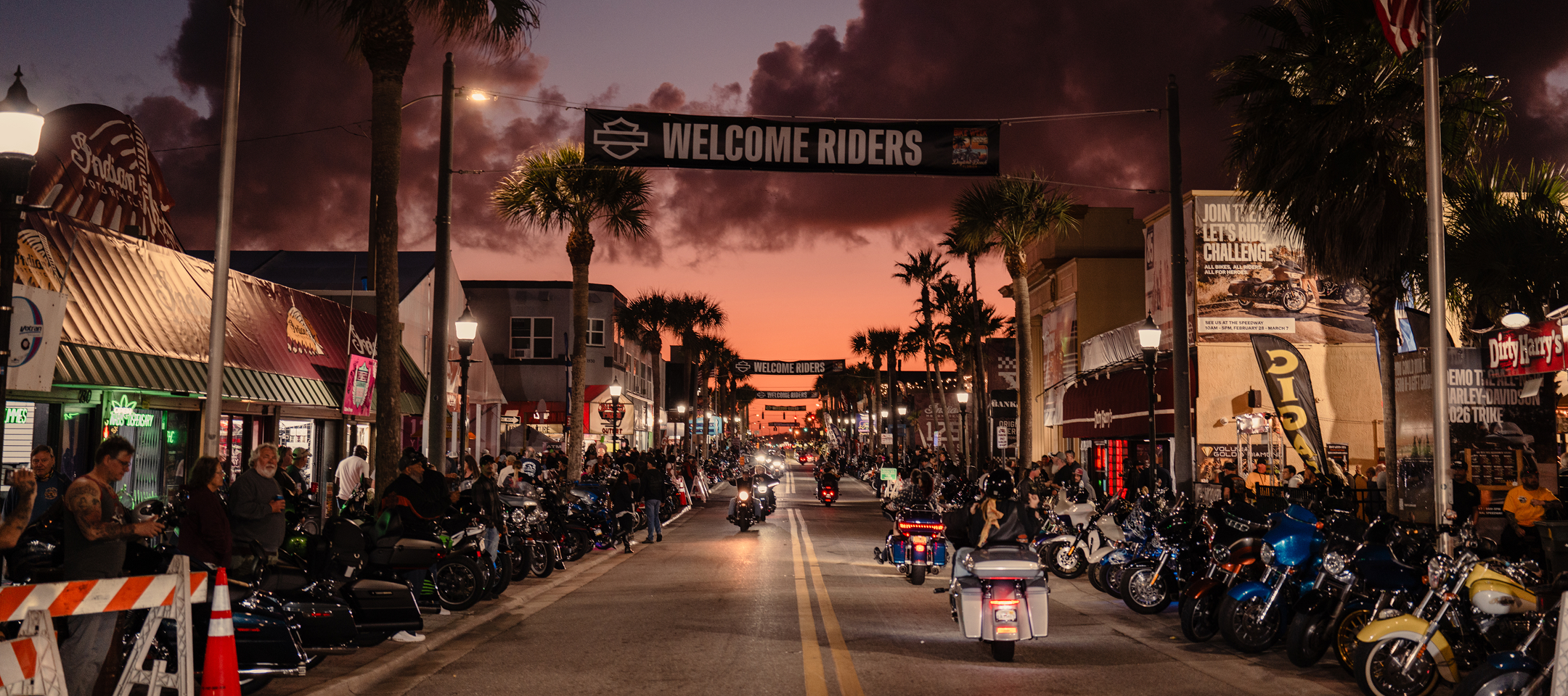 Daytona Beach Main Street at sunset, crowded with motorcycles under a Welcome Riders banner
