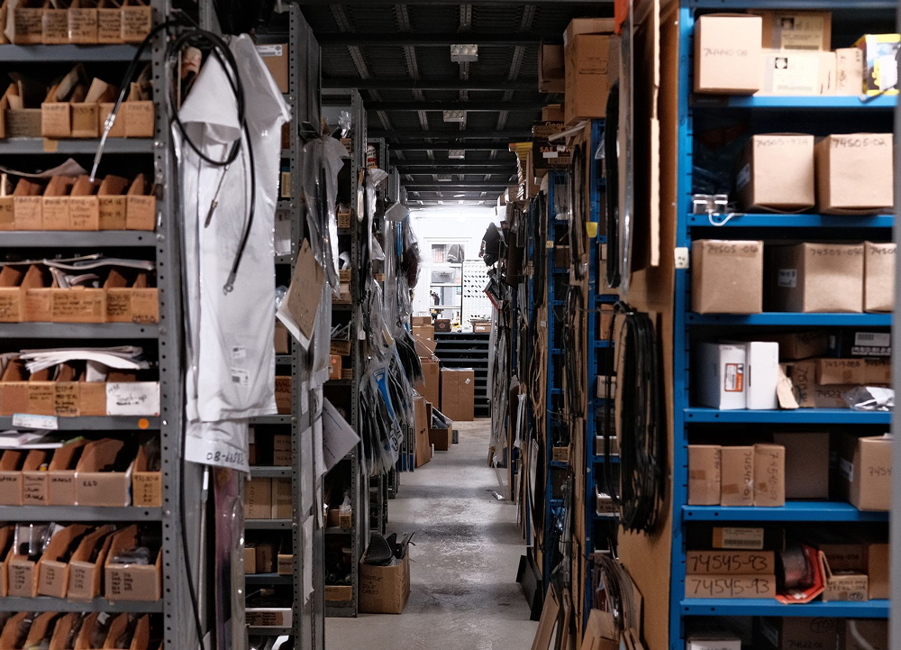 Aisle of organized H-D parts inventory with labeled boxes shelves and components in warehouse storage area