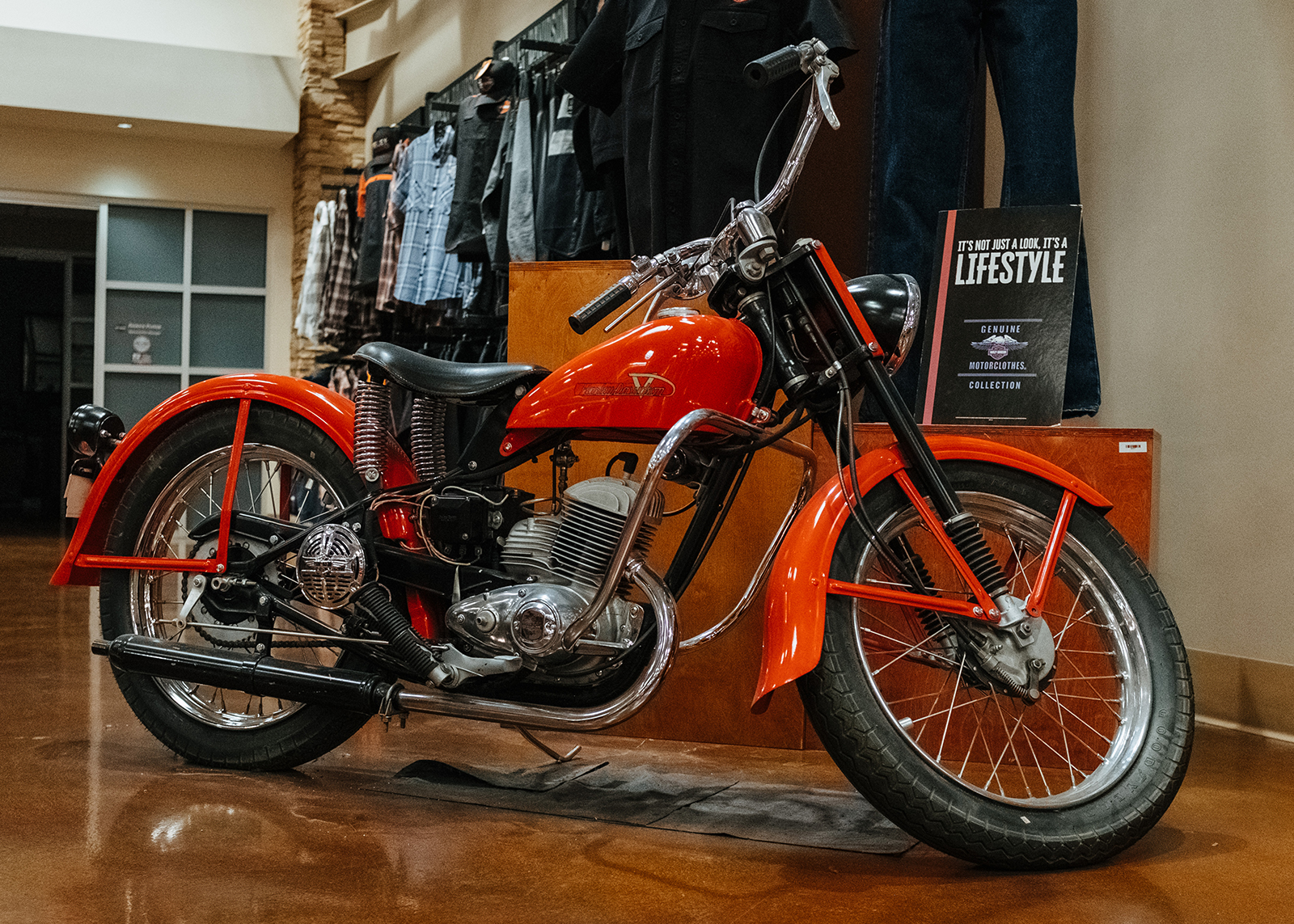 An orange vintage Harley-Davidson motorcycle is on display.