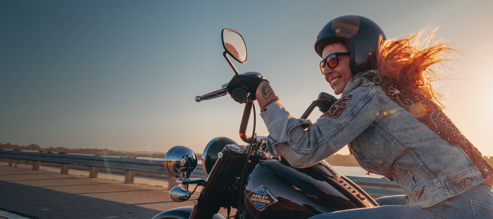 Woman leaning forward riding motorcycle smiling and hair blowing in the wind