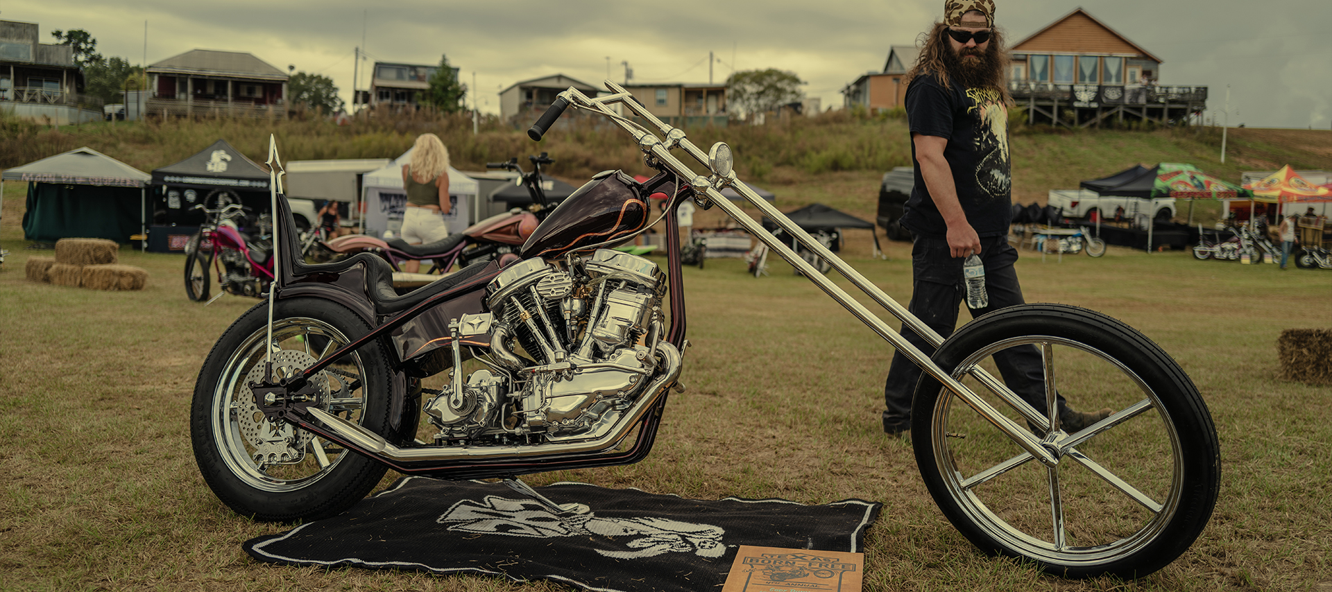 A man looks at a custom Harley-Davidson chopper with an extended rake as he walks past at the Born Free Texas motorcycle rally.