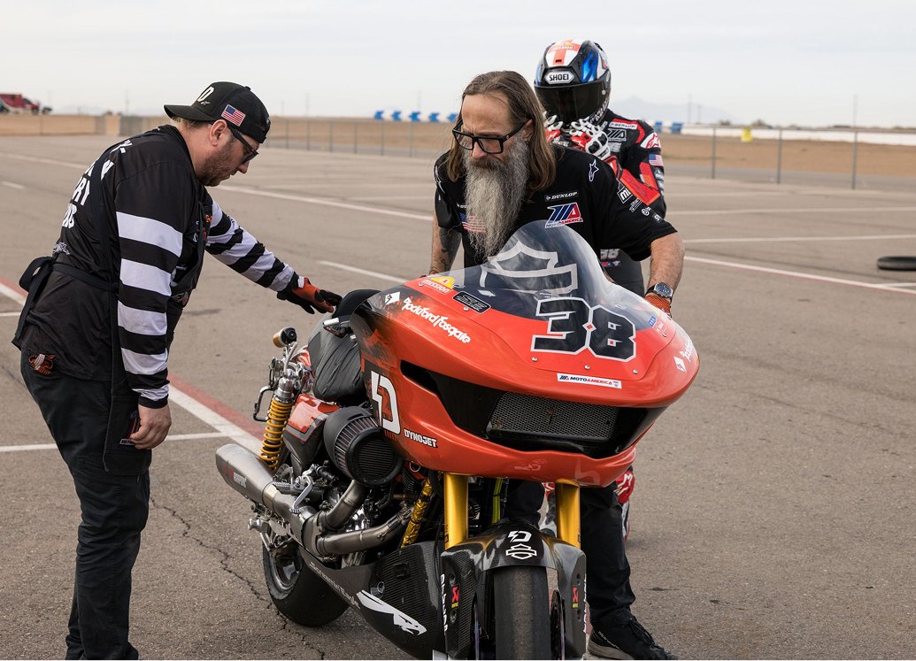 Harley-Davidson Racing crew members assist a rider preparing to take off on a race motorcycle in the pit lane