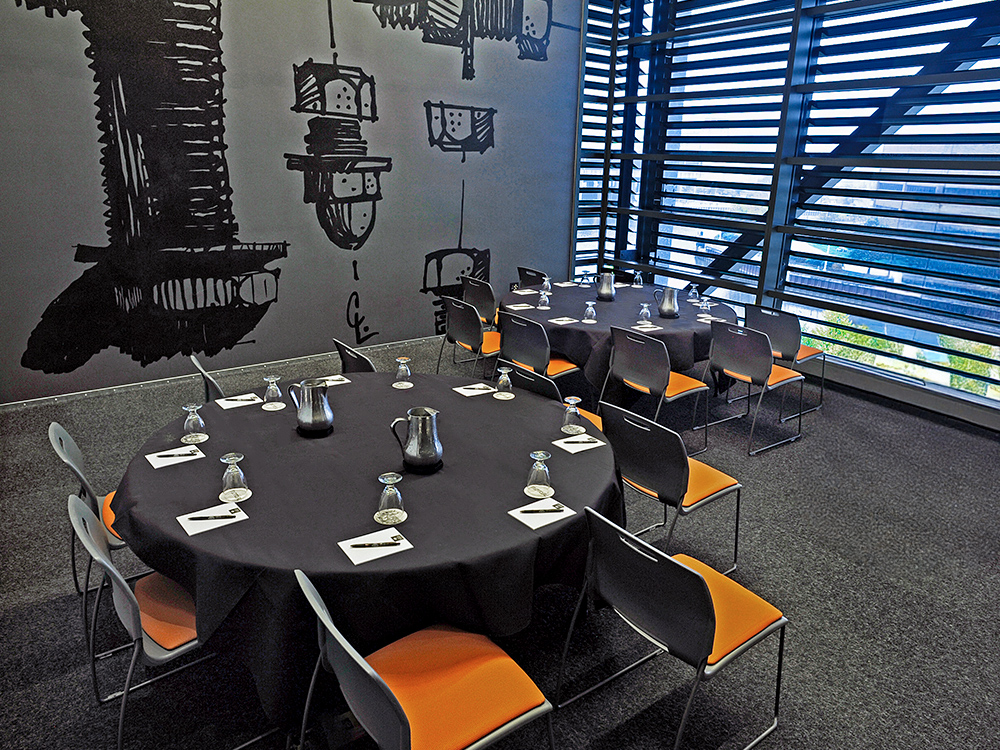 Round table setup with black linens and orange chairs in meeting room