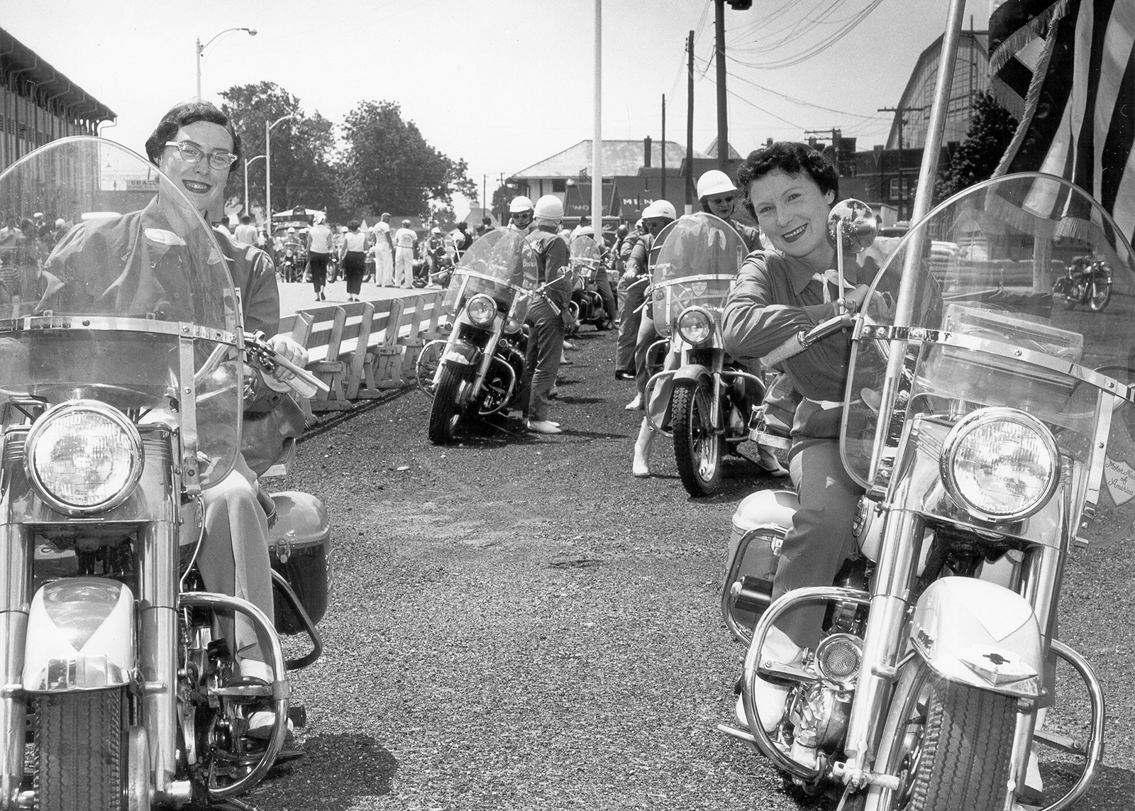 A vintage photo of a Motor Maid rally with several members lined up on their motorcycles before a parade.