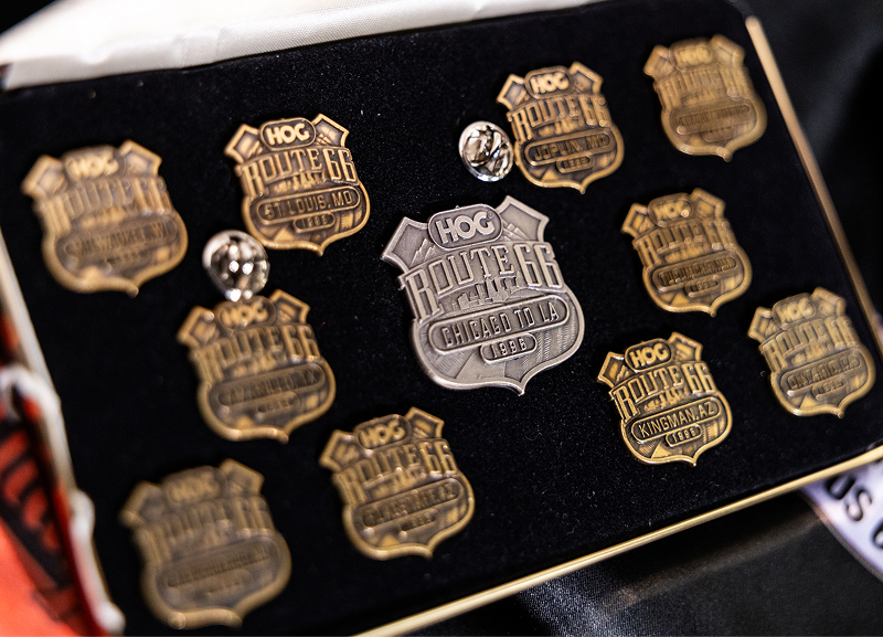 Close-up of 1996 Route 66 pins displayed in a case, featuring various HOG rally locations and badges