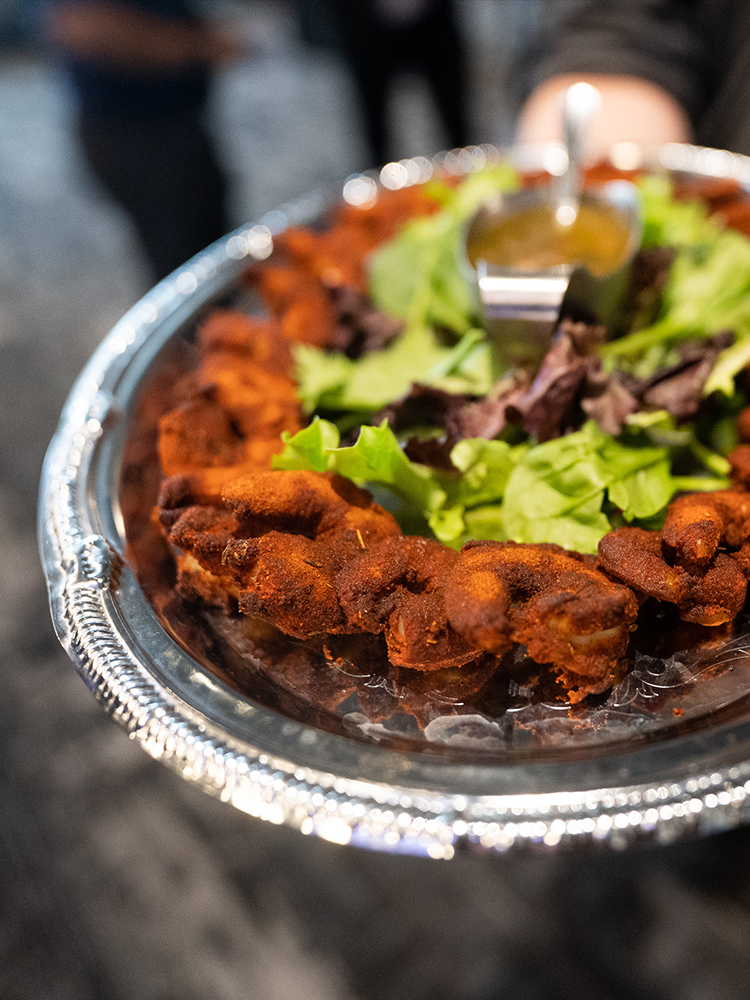 Fried chicken bites arranged around salad with dipping sauce on tray