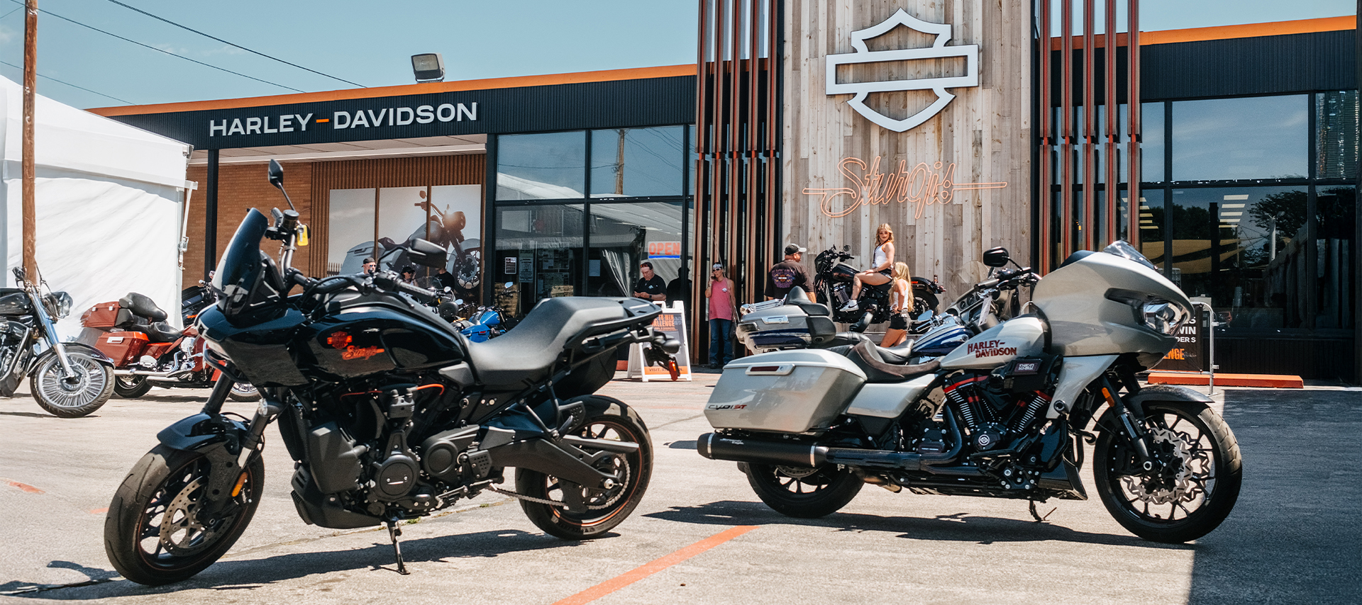 Harley-Davidson motorcycles parked outside the Sturgis Harley-Davidson dealership with visitors gathered in the background.
