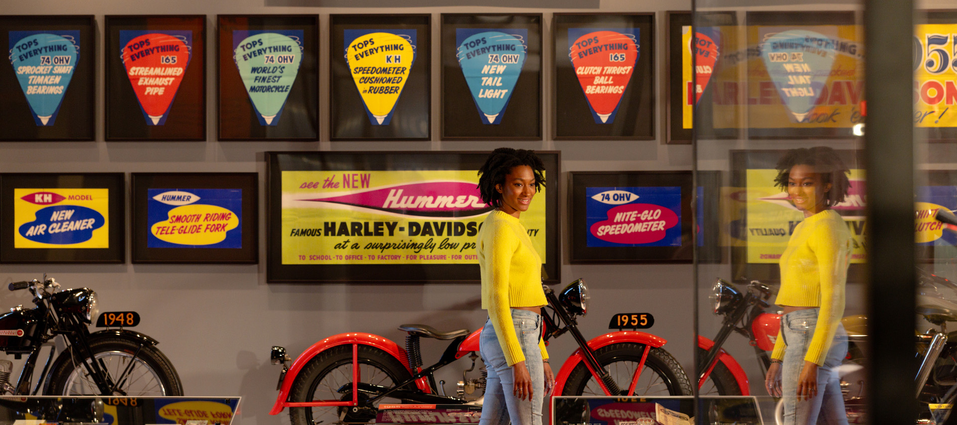 Visitor walking past vintage motorcycles with colorful sign display in museum