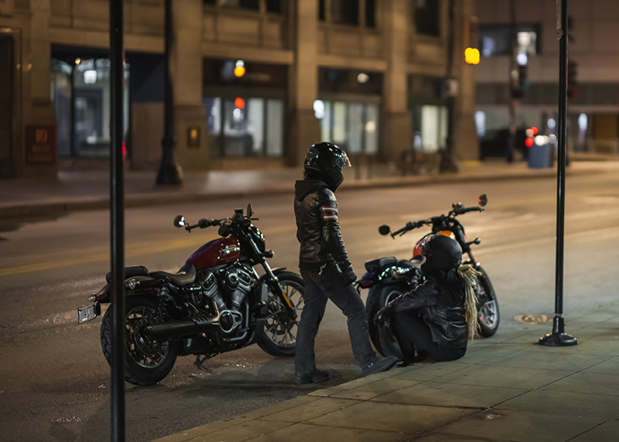 Two motorcyclists stopped on the side of city road