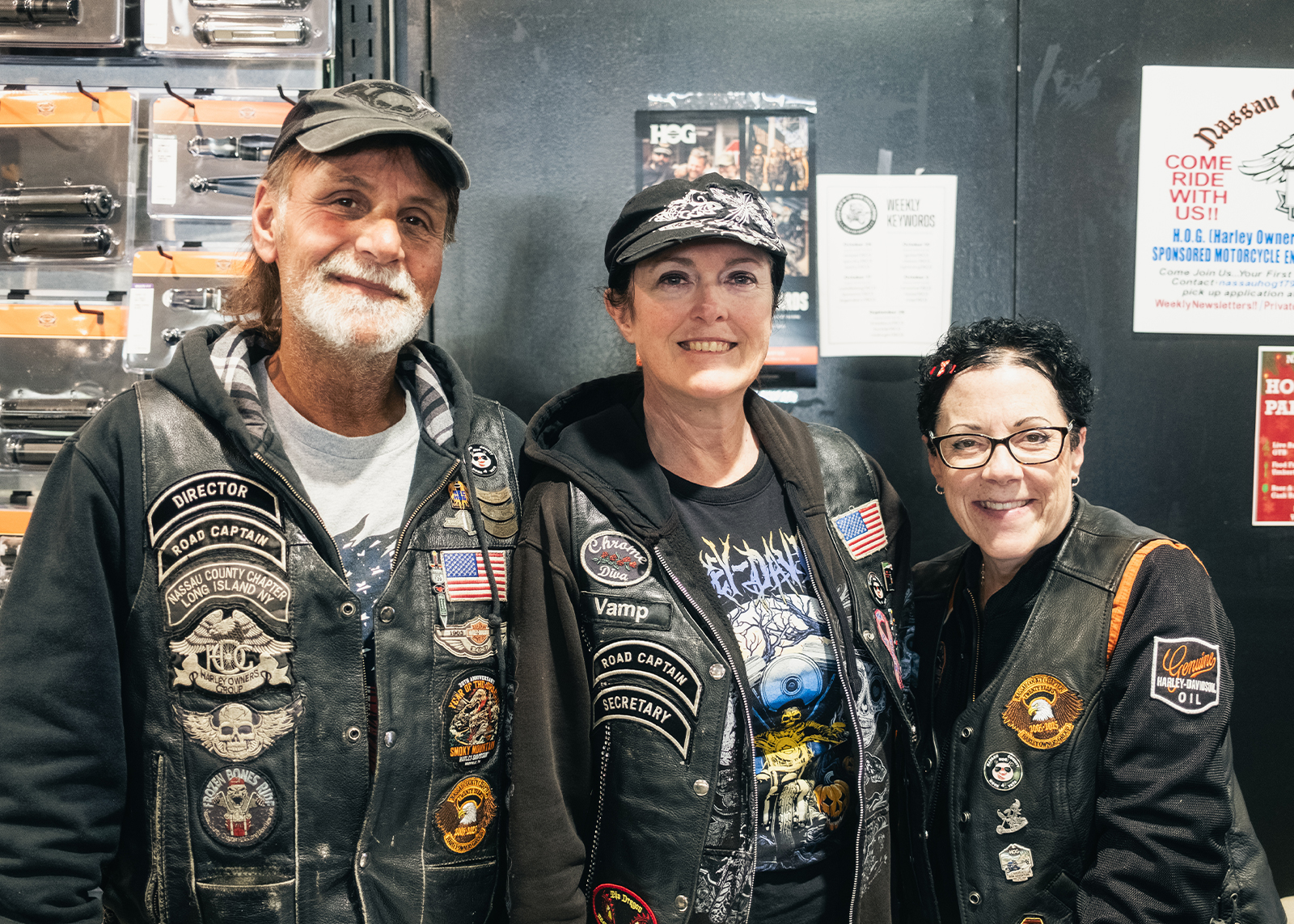 Three members of Nassau County H.O.G. Chapter 1797 pose for a photo, wearing vests covered with patches.