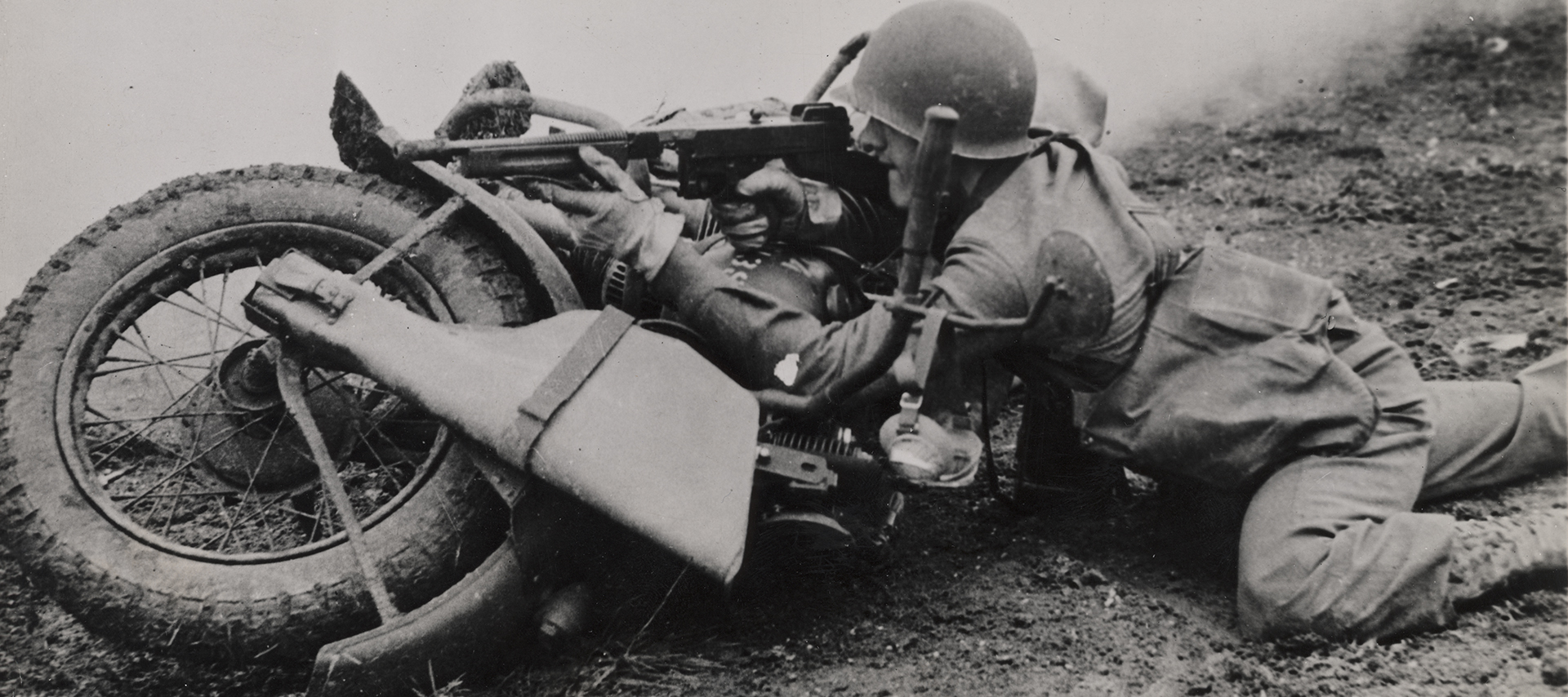 Soldier uses his motorcycle as a barrier to prop his rifle on 