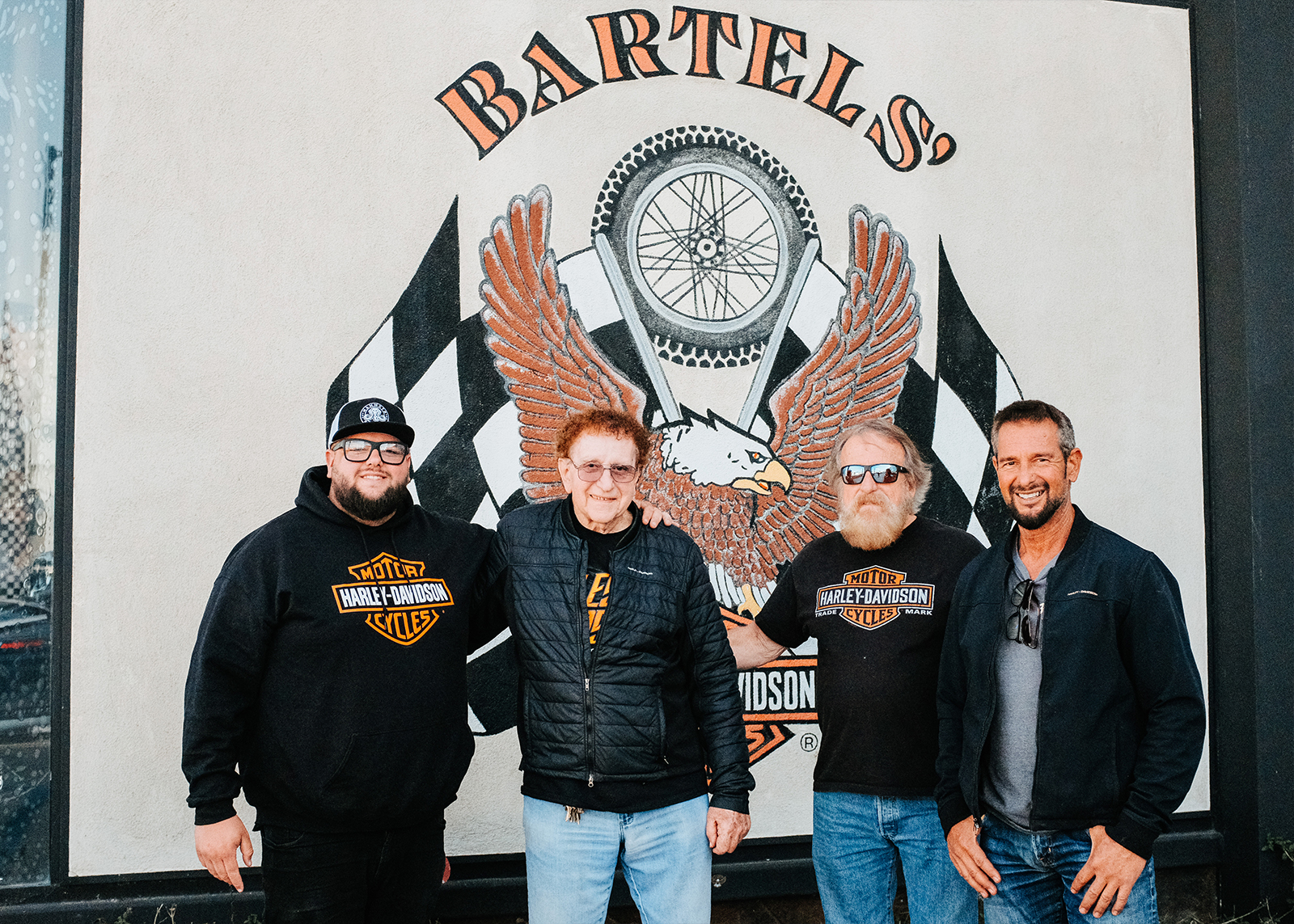 Bartel’s owner and staff pose for a photo in front of a dealership sign.