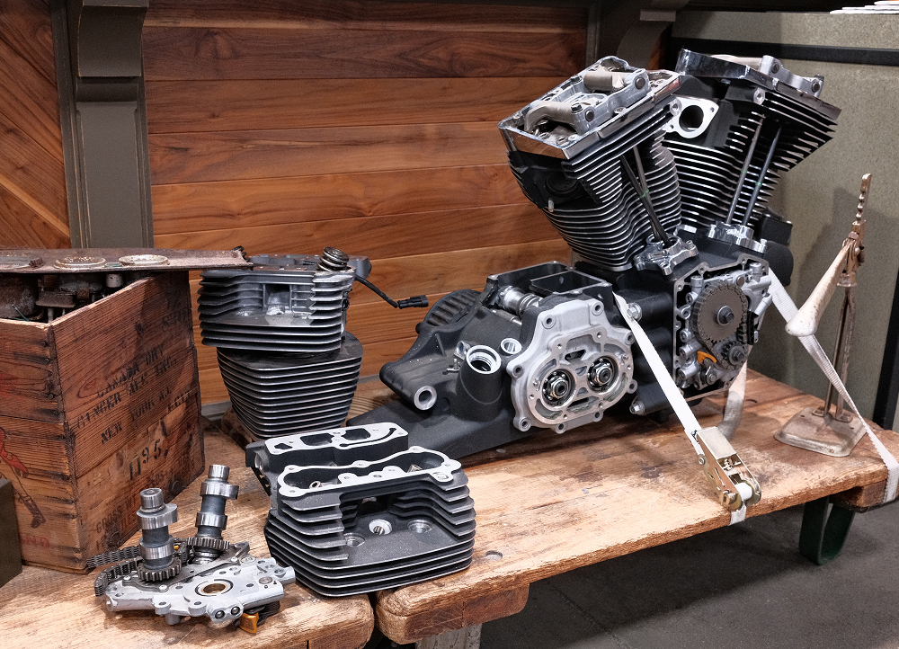 Disassembled Harley-Davidson engine components arranged on wooden workbench with tools and parts