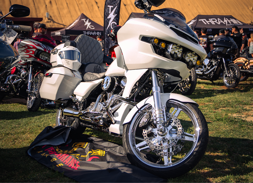 White touring Harley-Davidson motorcycle with chrome wheels and custom bodywork parked at an outdoor bike show