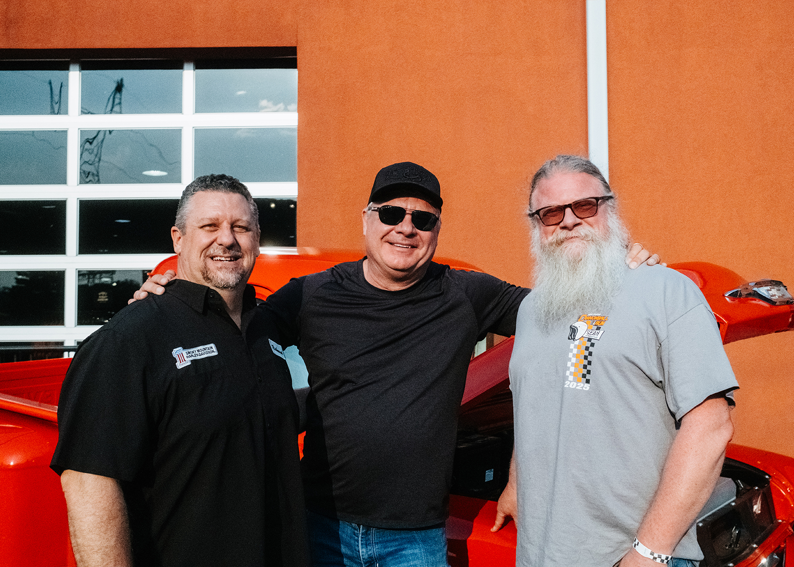 Three members of Smokey Mountain staff pose in front of the Smokey Mountain Harley-Davidson dealership.