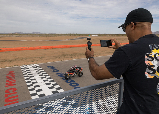 The author films a motorcycle speeding across the finish line on a desert racetrack from above