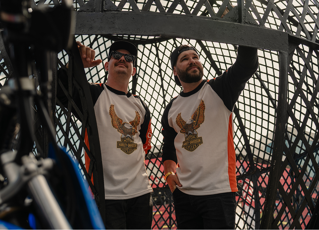 The Ives Brothers posing inside a metal mesh globe with a bike visible in the foreground