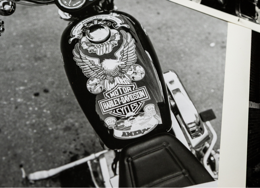 Black‑and‑white photo of a motorcycle fuel tank featuring the eagle‑themed ‘76 Bicentennial artwork