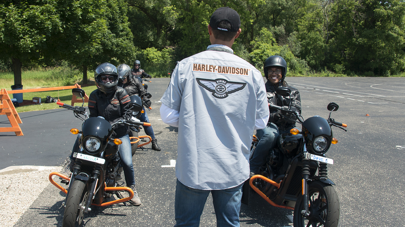 People learning to ride a motorcycle on a training range