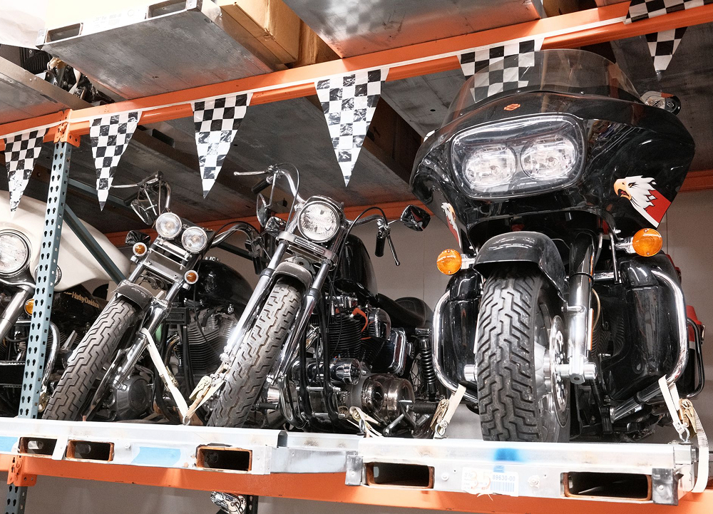 Vintage H-D motorcycles lined on display rack with checkered flags and overhead shop lighting