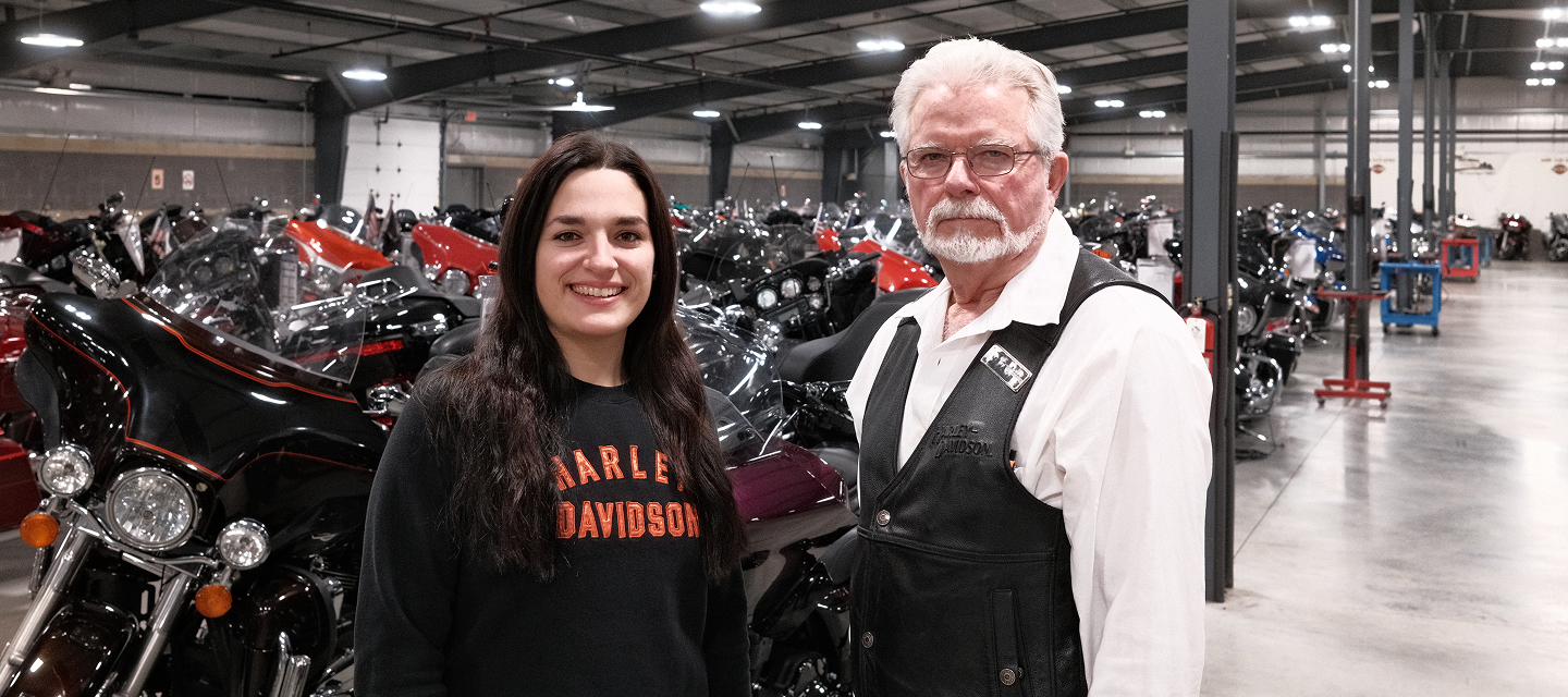 H-D of Madison’s Virgil “Wolf” Schulenberg and his daughter, Rebecca Schulenburg pose in their storage facility, surrounded by rows of Harley‑Davidson bikes under bright warehouse lighting