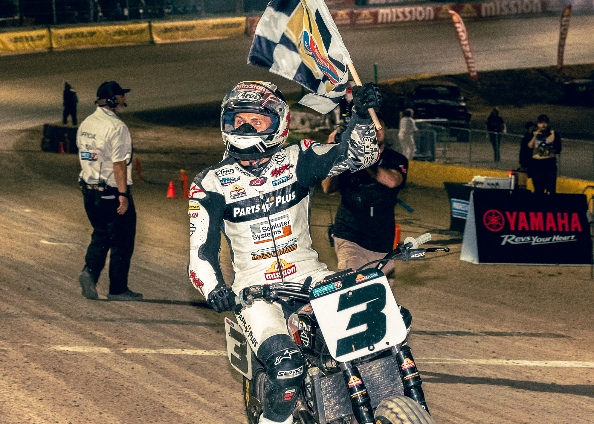   Briar Bauman carries a checkered flag as he circles a dirt track after winning a race