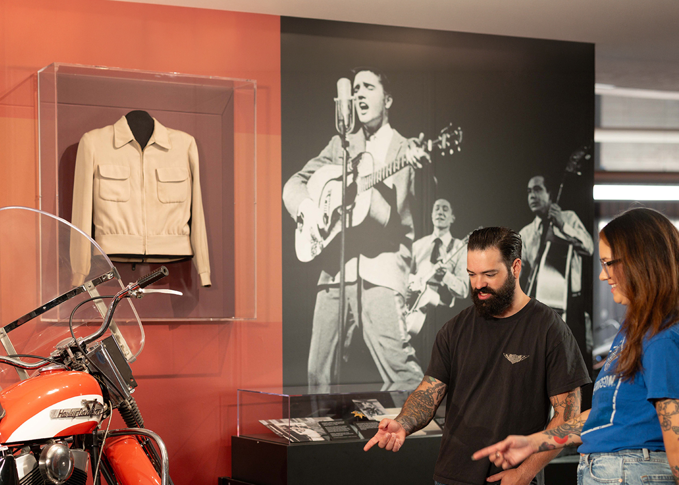 Visitors exploring Harley-Davidson exhibit with vintage motorcycle and music display