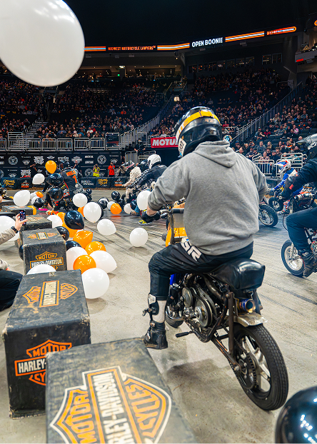 Motorcycle racers navigate around balloons on the arena floor during a live show
