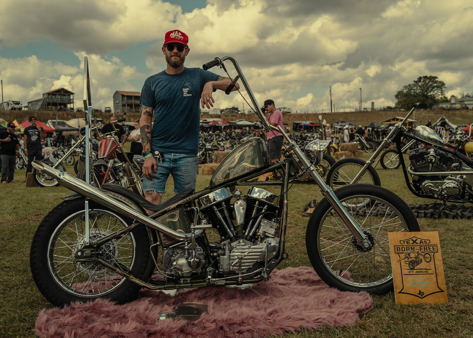 Justin Haynie stands beside his custom 1950 Harley-Davidson Panhead at the Born Free Texas rally under sunny skies.