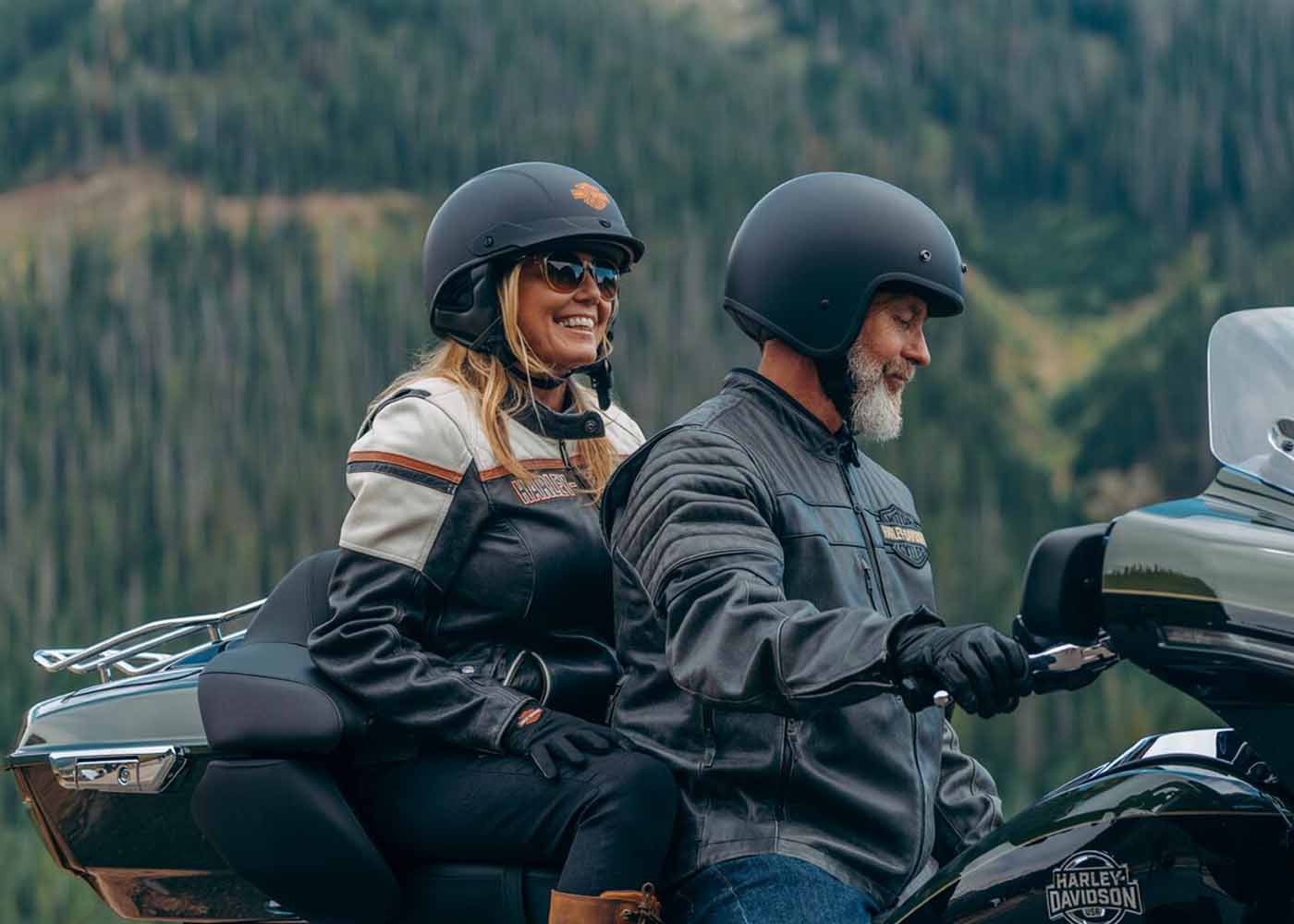 man and woman in helmets on a Harley-Davidson motorcycle