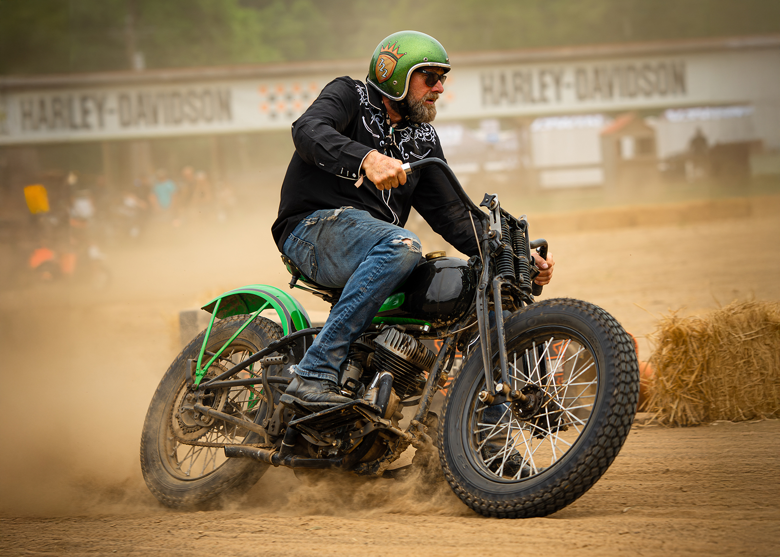 A man races his old school Harley around a dirt track.