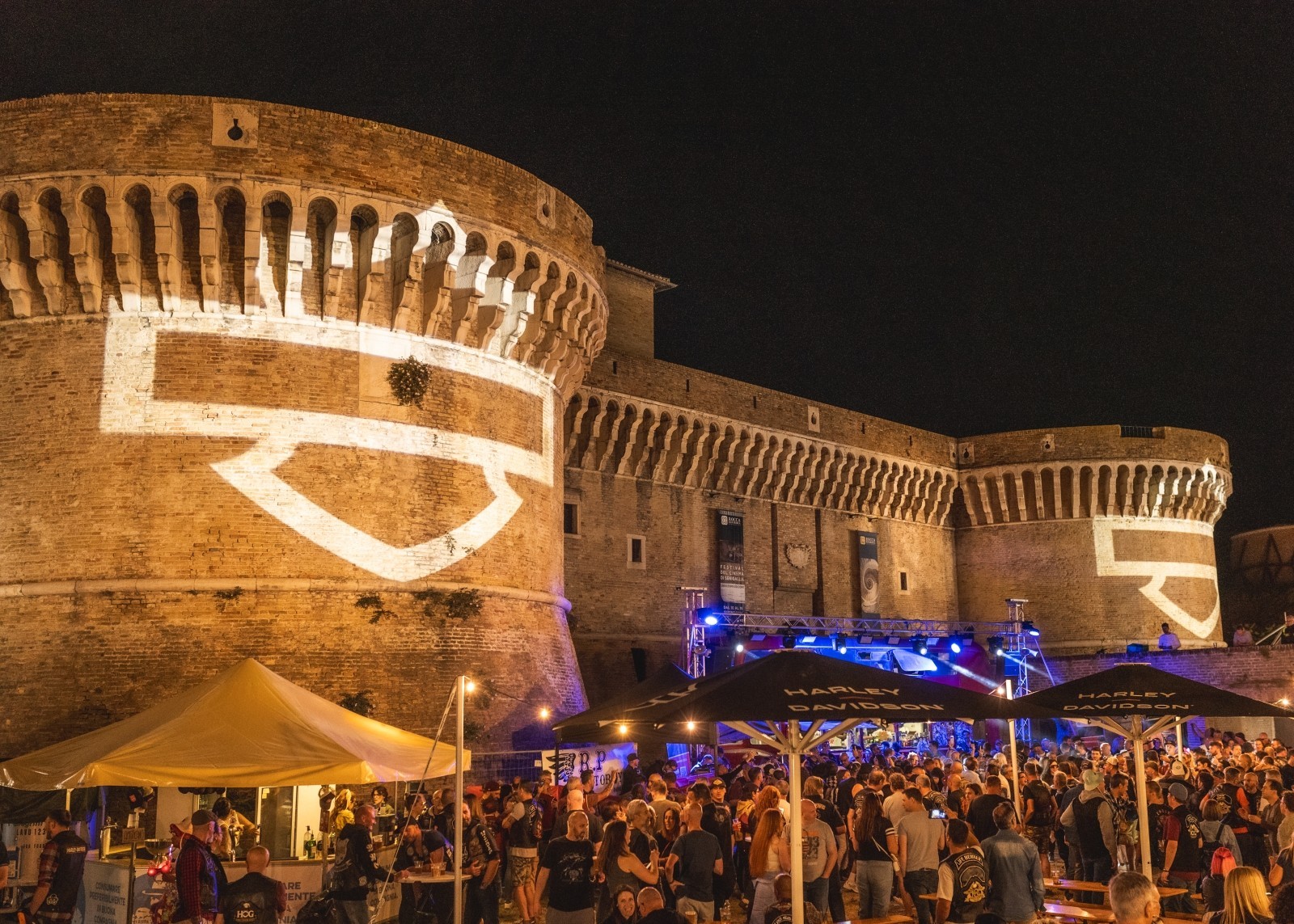 Aerial night view of a bustling shopping village in Senigaliya, filled with crowds and lights.