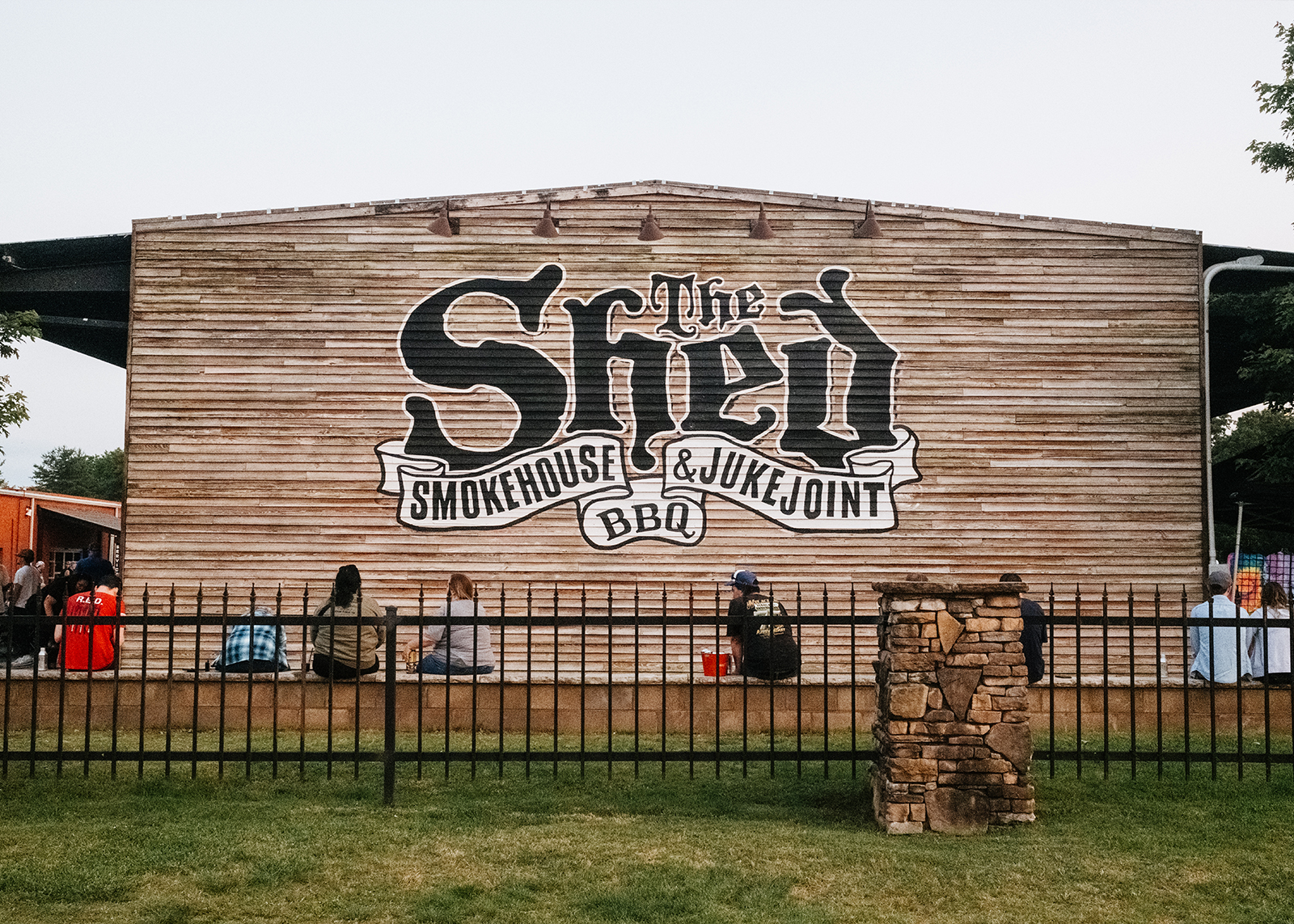 The Shed BBQ logo painted on the wood paneled outside wall of the building.