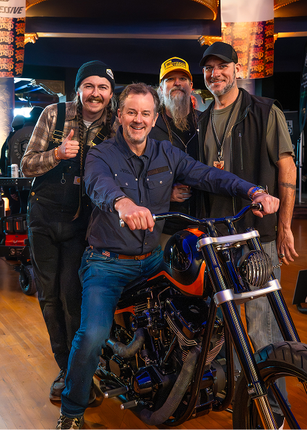Harley-Davidson CEO Artie Starrs sits on a custom motorcycle surrounded by three people