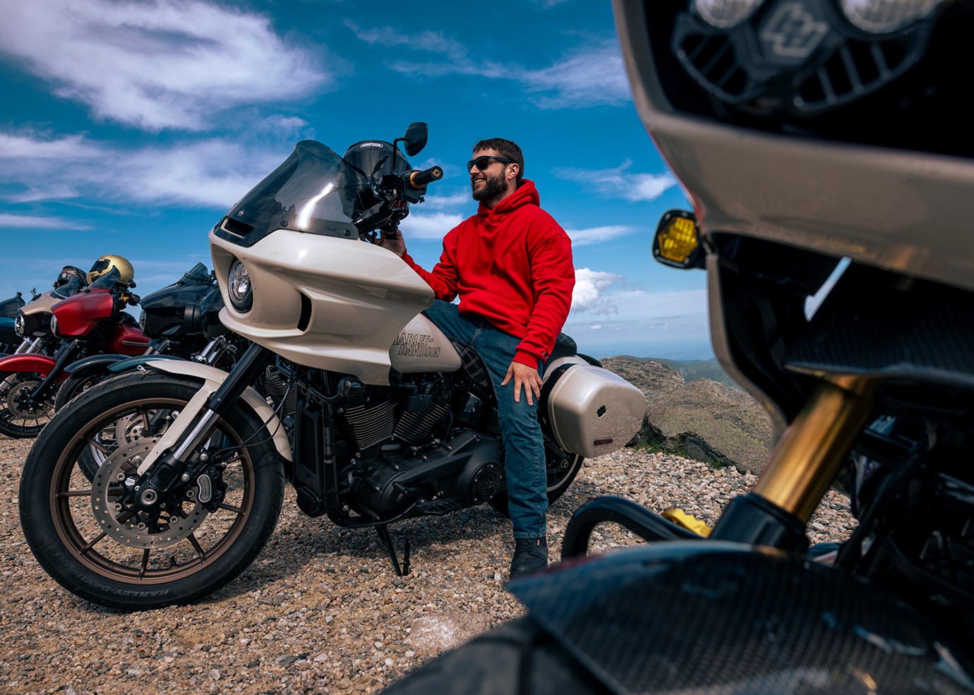 Motociclista de jaqueta vermelha sentado em uma motocicleta touring em um mirante de montanha