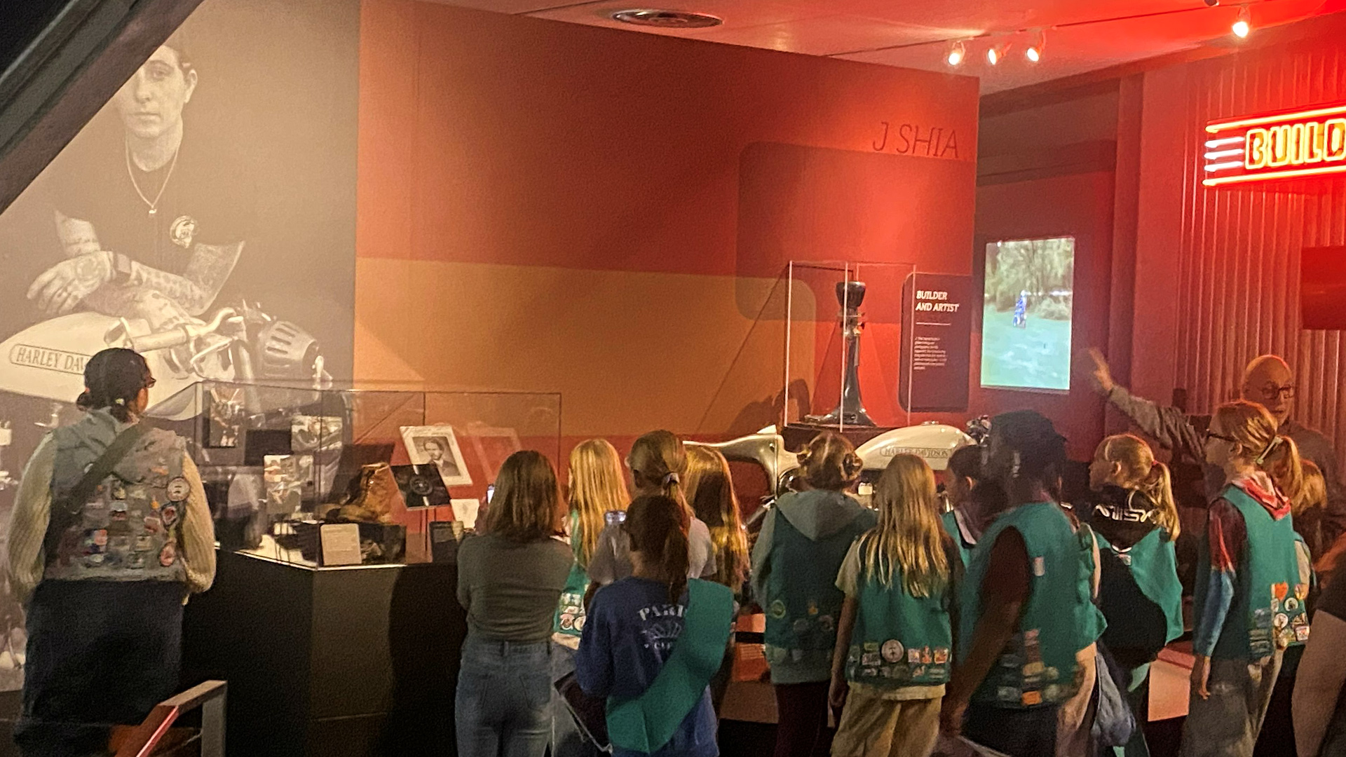 Group of visitors viewing motorcycle exhibit with large portrait and display cases
