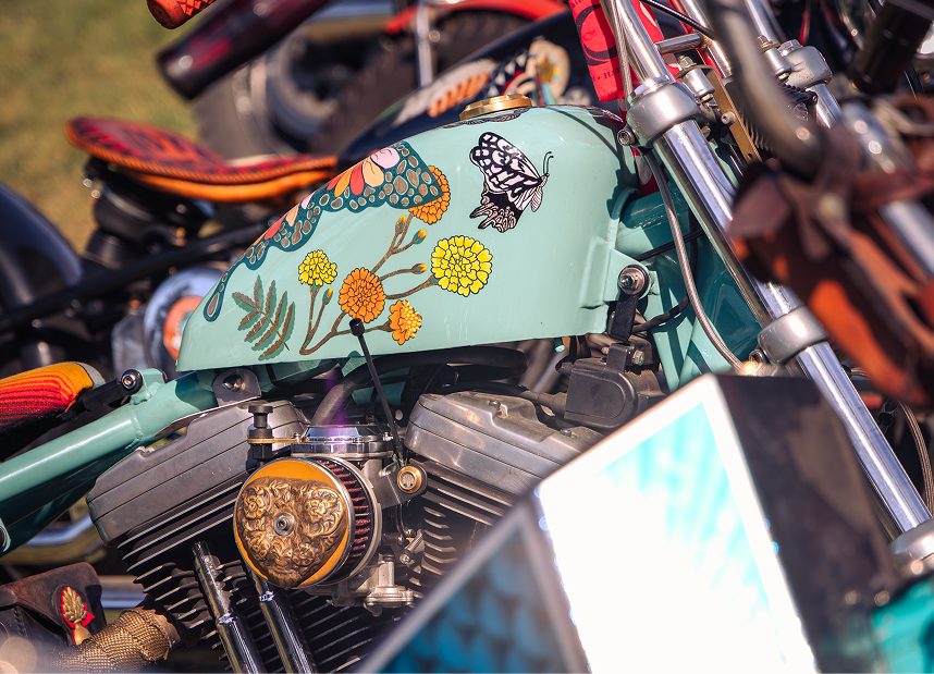 Close-up of a custom motorcycle tank with floral artwork and chrome engine components