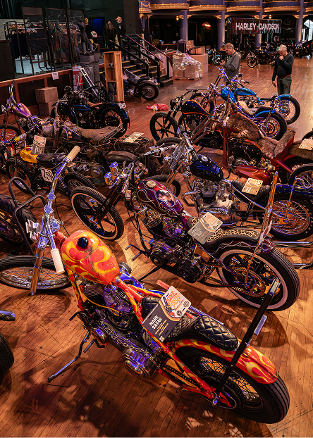Rows of colorful custom motorcycles lined up on the show floor in a large indoor venue