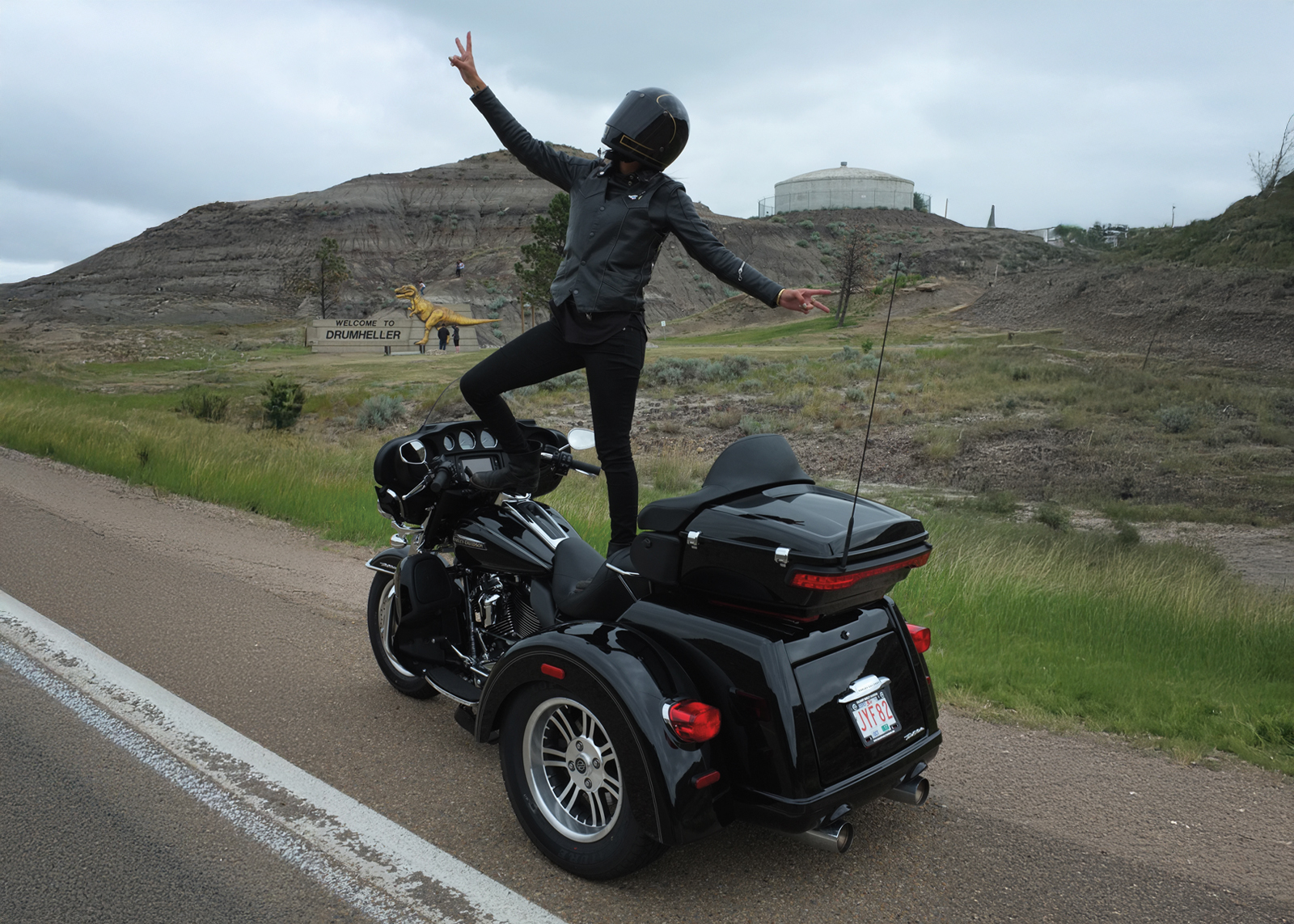 Person standing on their trike infront of Drumheller sign