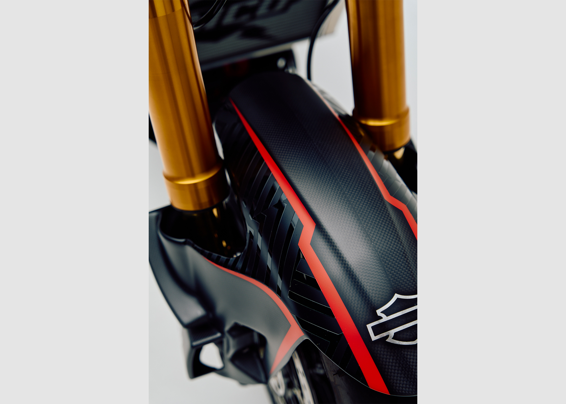 Close-up of the custom Pan America ST’s front fender with carbon fiber texture, red accent lines, and Harley-Davidson logo.