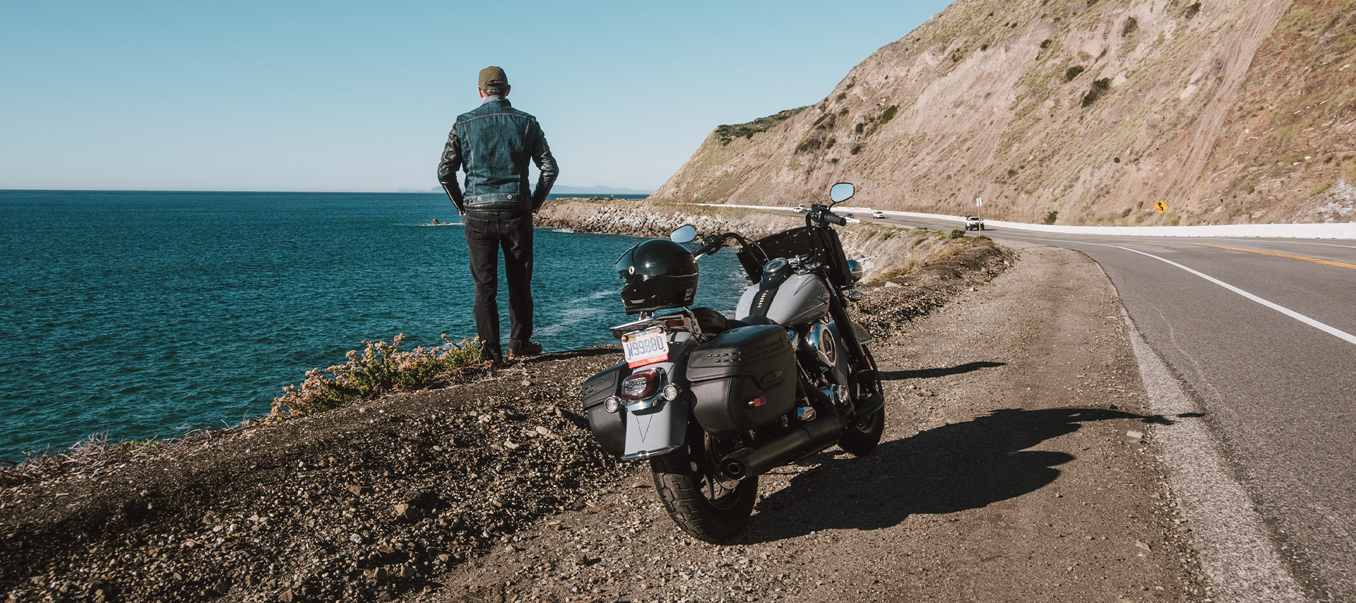 The author standing looking at the ocean on a coastal highway shoulder with his Harley-Davidson Heritage Classic parked nearby