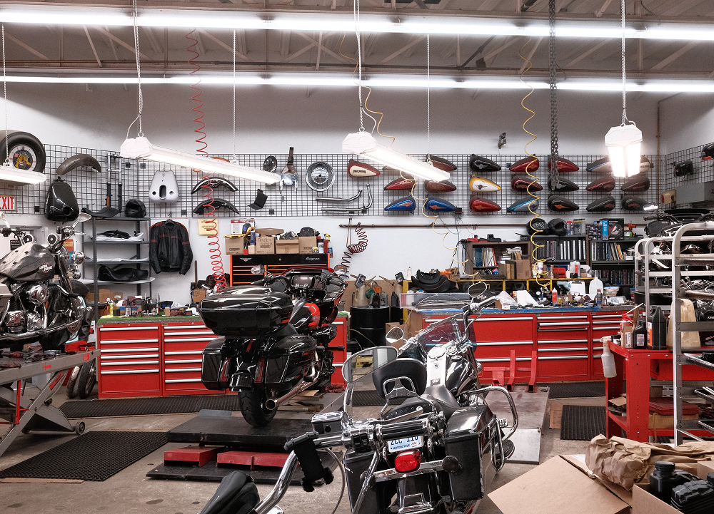 Wide view of Precision H-D service department with motorcycles on lifts red tool cabinets and vintage tanks lined along wall