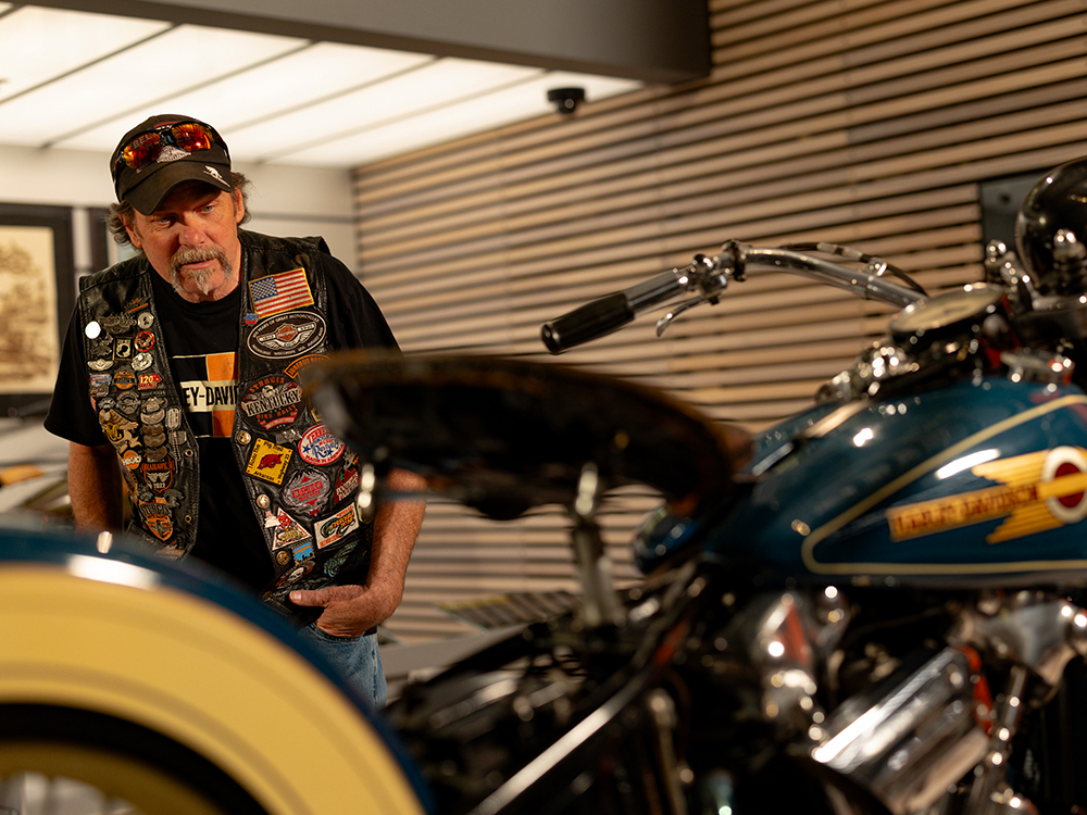 Visitor viewing vintage Harley-Davidson motorcycle in museum exhibit