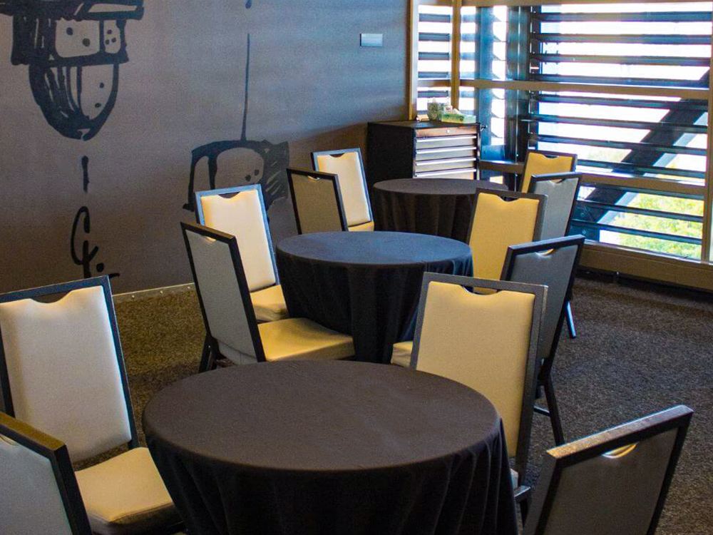Round tables with black linens and chairs in modern meeting room